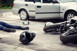 motorcycle rider on the ground with helmet off and motorcycle on the side after an accident