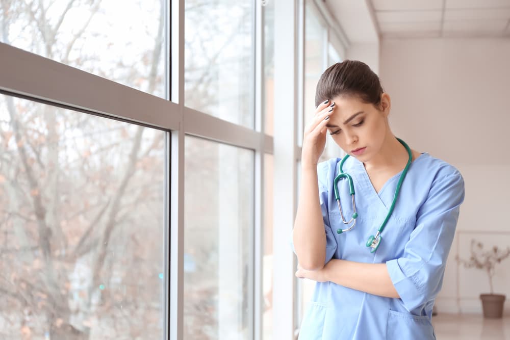 sad nurse thinking in hospital lobby