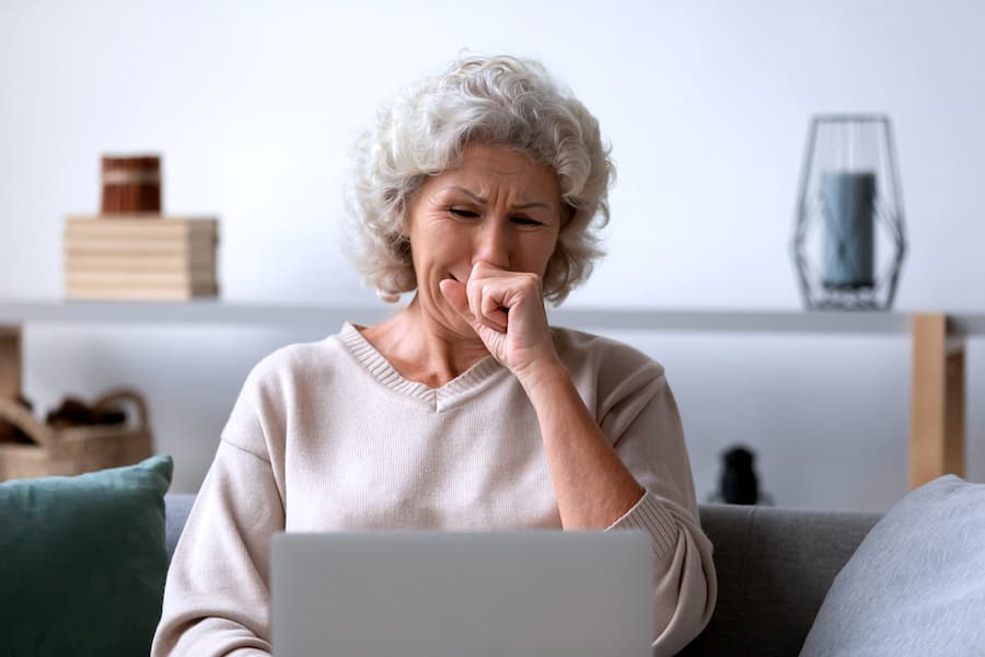 depressed senior older woman crying in front of laptop