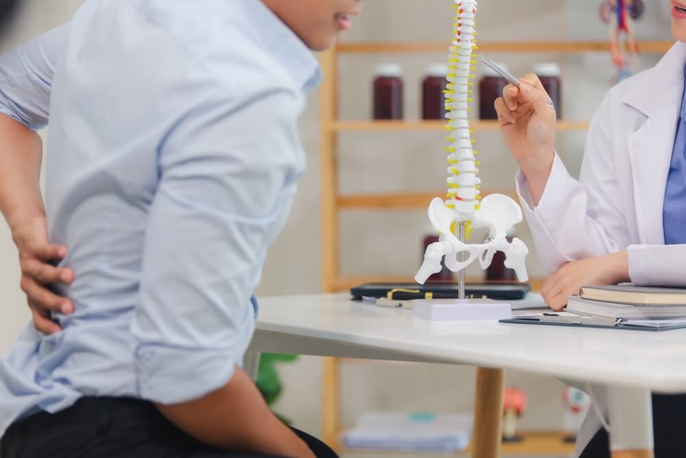 An orthopedic doctor shows a spinal model to a patient in a human spinal hospital.
