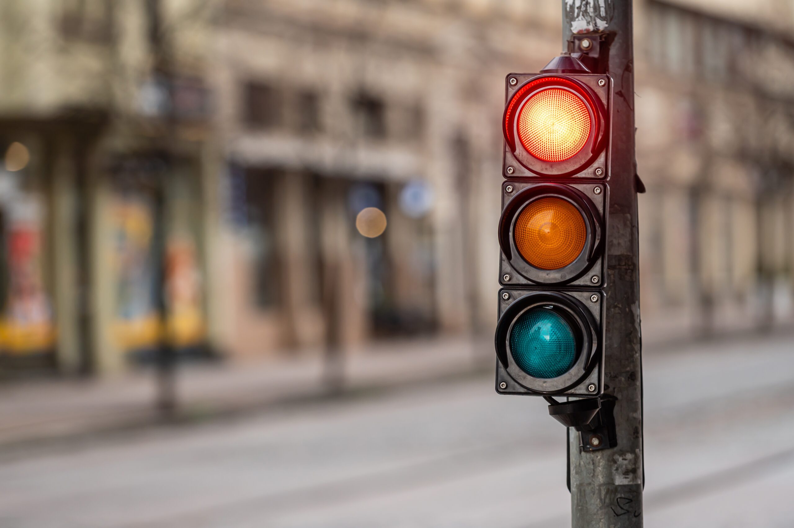 intersection light on red with blurred out city view in the background