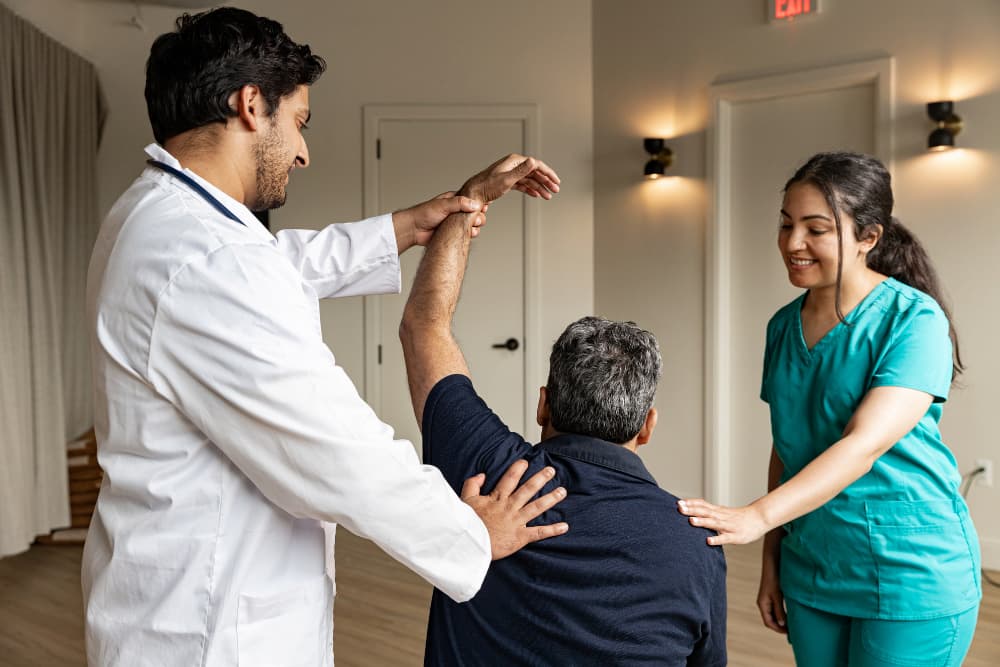 Doctor and Nurse assisting elderly man with shoulder mobility