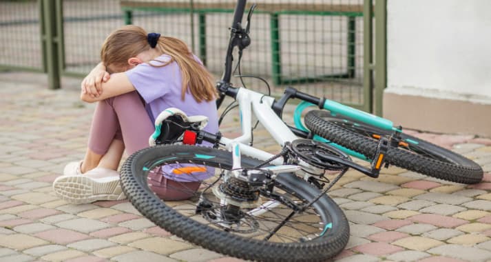 Sad child sitting after bicycle fall
